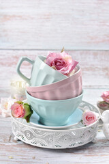 a stack of pastel color bowls and cups with roses