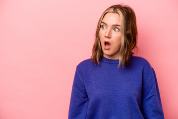 Young caucasian woman isolated on pink background being shocked because of something she has seen.