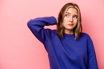 Fototapeta premium Young caucasian woman isolated on pink background touching back of head, thinking and making a choice.