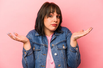 Young caucasian woman isolated on pink background doubting and shrugging shoulders in questioning...