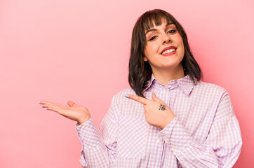 Young caucasian woman isolated on pink background excited holding a copy space on palm.
