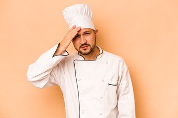 Hispanic chef man isolated on beige background being shocked, she has remembered important meeting.