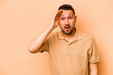 Young hispanic man isolated on beige background shouts loud, keeps eyes opened and hands tense.