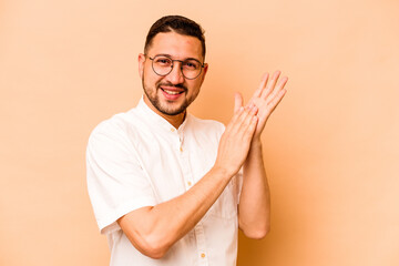 Young hispanic man isolated on beige background feeling energetic and comfortable, rubbing hands confident.