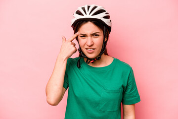 Young caucasian woman wearing helmet isolated on pink background showing a disappointment gesture with forefinger.