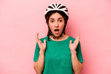 Young caucasian woman wearing helmet isolated on pink background surprised and shocked.