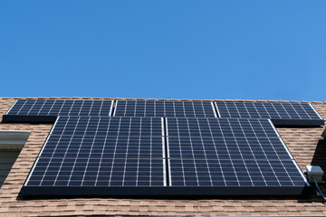 A residential solar panel array mounted on an asphalt shingle roof with copy space