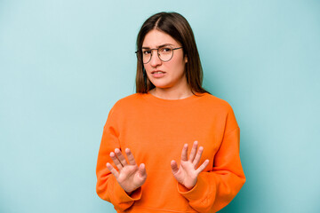 Young caucasian woman isolated on blue background rejecting someone showing a gesture of disgust.