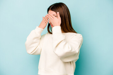 Young caucasian woman isolated on blue background afraid covering eyes with hands.