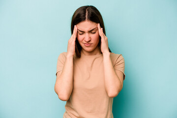 Young caucasian woman isolated on blue background having a head ache, touching front of the face.