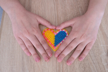 close-up of heart, children's hands creating perler bead patterns, make flag of ukraine using...