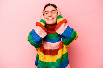 Young caucasian woman isolated on pink background laughs joyfully keeping hands on head. Happiness concept.