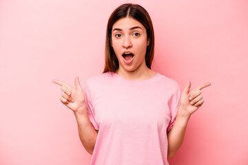 Young caucasian woman isolated on pink background pointing to different copy spaces, choosing one of them, showing with finger.