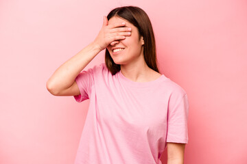 Young caucasian woman isolated on pink background covers eyes with hands, smiles broadly waiting for a surprise.