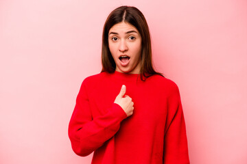 Young caucasian woman isolated on pink background surprised pointing with finger, smiling broadly.