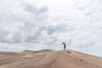 Obraz na płótnie Canvas Photo with copy space of a woman gesturing freedom in the middle of a desert in a cloudy day