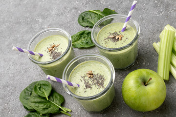 Healthy green spinach smoothie in glass jars and other ingredients on a gray concrete background. Superfoods, detox, diet, healthy food. Celery, apple, spinach, spinach, and banana.