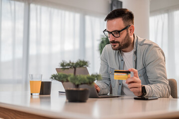Businessman doing online transaction from laptop with credit card at office desk