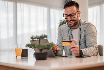 Happy professional doing online transaction with credit card from laptop