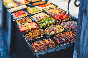 Delicious traditional Liége waffles with colorful toppings on display in a store window in Liége, Belgium