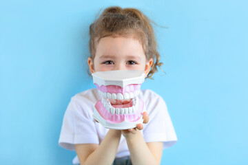 Little cute funny girl holding tooth jaw. Kid training oral hygiene. Child learning brushing, cleaning teeth. Prevention of caries in children. children dentistry