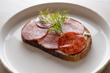 closeup sandwich with dried sausage, brown bread, butter