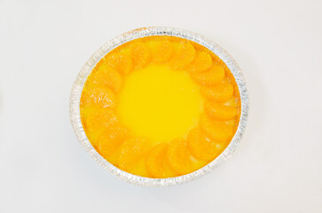 Orange cake decorated with fresh oranges placed on a white background.