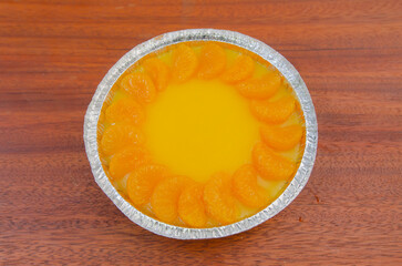 Orange cake decorated with fresh oranges on a wooden table.