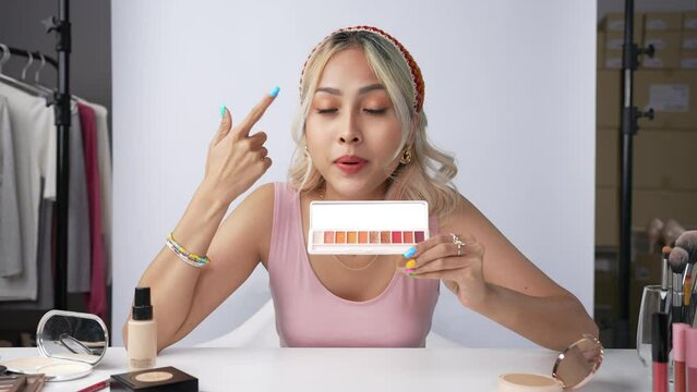 Young beautiful Asian woman and professional beauty make up artist vlogger or blogger recording makeup tutorial to share on website or social media. Business online influencer on social media concept.
