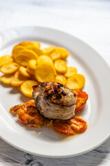 pork tenderloin in bacon on pepper with potatoes and tomatoes