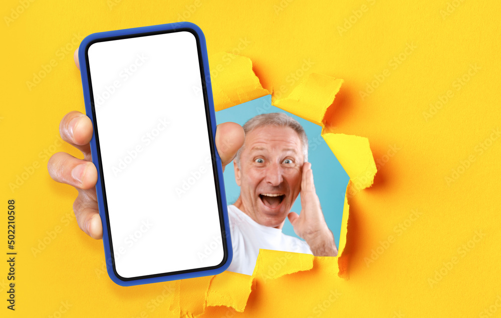 Poster excited man showing white empty smartphone screen through torn paper