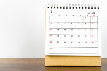 July 2022 desk calendar on wooden background.