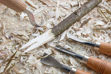 Selbst geschnitzter Holzlöffel Kochlöffel Pfannenkratzer Gabel bearbeitet mit Messer Werkzeug auf einer Werkbank mit Holzspäne, Deutschland - obrazy, fototapety, plakaty