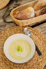 Celery cream soup in a bowl on a rustic wooden table. Healthy food concept, close up with selective focus. 