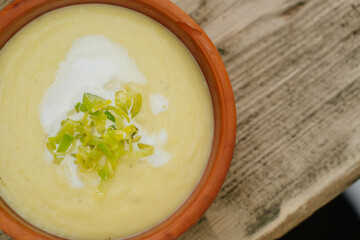 Celery cream soup in a bowl on a rustic wooden table. Healthy food concept, close up with selective focus. 