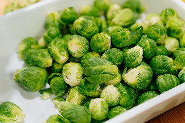 Obraz premium White dish with fresh green Brussels sprouts. Top view, close-up. Healthy food concept.