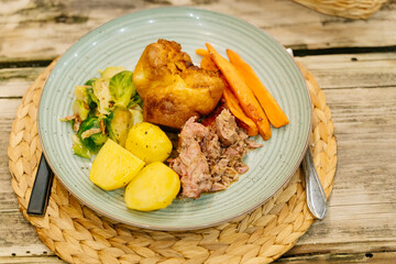 A plate of delicious rooster pot roast with potatoes and carrots. Brussels sprouts garnish and homemade English bread