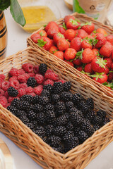 Fresh berries in a wicker basket. Strawberries, raspberries, blackberries, mulberries. Healthy organic food concept. 