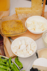 Close-up of assorted cheese with fresh honey and honeycomb placed on the table. The cheese is cut into pieces. Healthy food concept