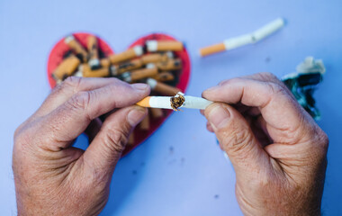 Man holding broken cigarette in hands. Stop smoking. Cardiology risk of heart attack. Cigarette,...