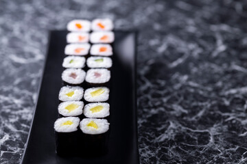 Obraz na płótnie Canvas set of sushi rolls with seafood on a black stone background
