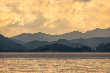 Sea tropical landscape with mountains and fjords. Vacation recreation holiday travel adventure concept. Mountain, ocean beach and cloudy sky background in orange yellowish color tones