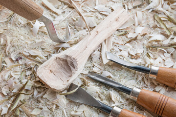 Selbst geschnitzter Holzlöffel Kochlöffel Pfannenkratzer Gabel bearbeitet mit Messer Werkzeug auf einer Werkbank mit Holzspäne, Deutschland
