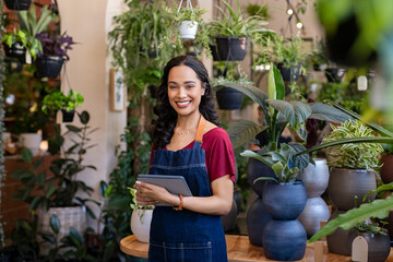 Successful small business owner holding digital tablet in flower shop