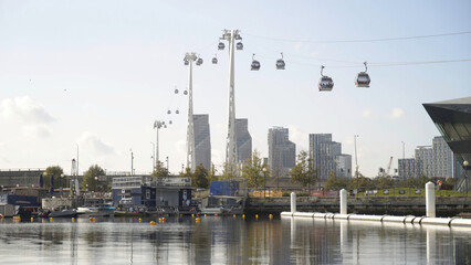 Beautiful view of promenade and modern city with cable car. Action. Beautiful panorama with cable car passing over canal on background of modern city