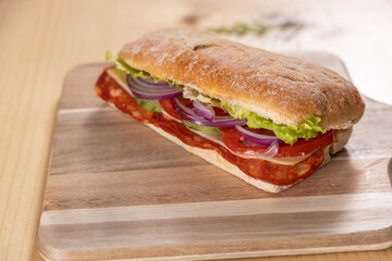 Sandwich with meat, salad, tomato and cheese on a wooden board