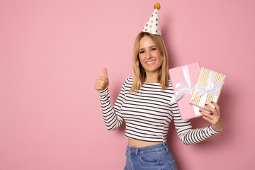 Portrait of a smiling pretty young woman holding gift boxes isolated over pink background