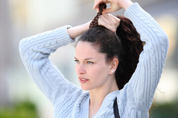 Casual woman doing ponytail in the street