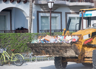 Close-up of a bulldozer hauling trash on an urban street in Mexico