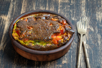 Frittata with egg, tomato, pepper, onion and cheese on wooden table. Italian egg omelette